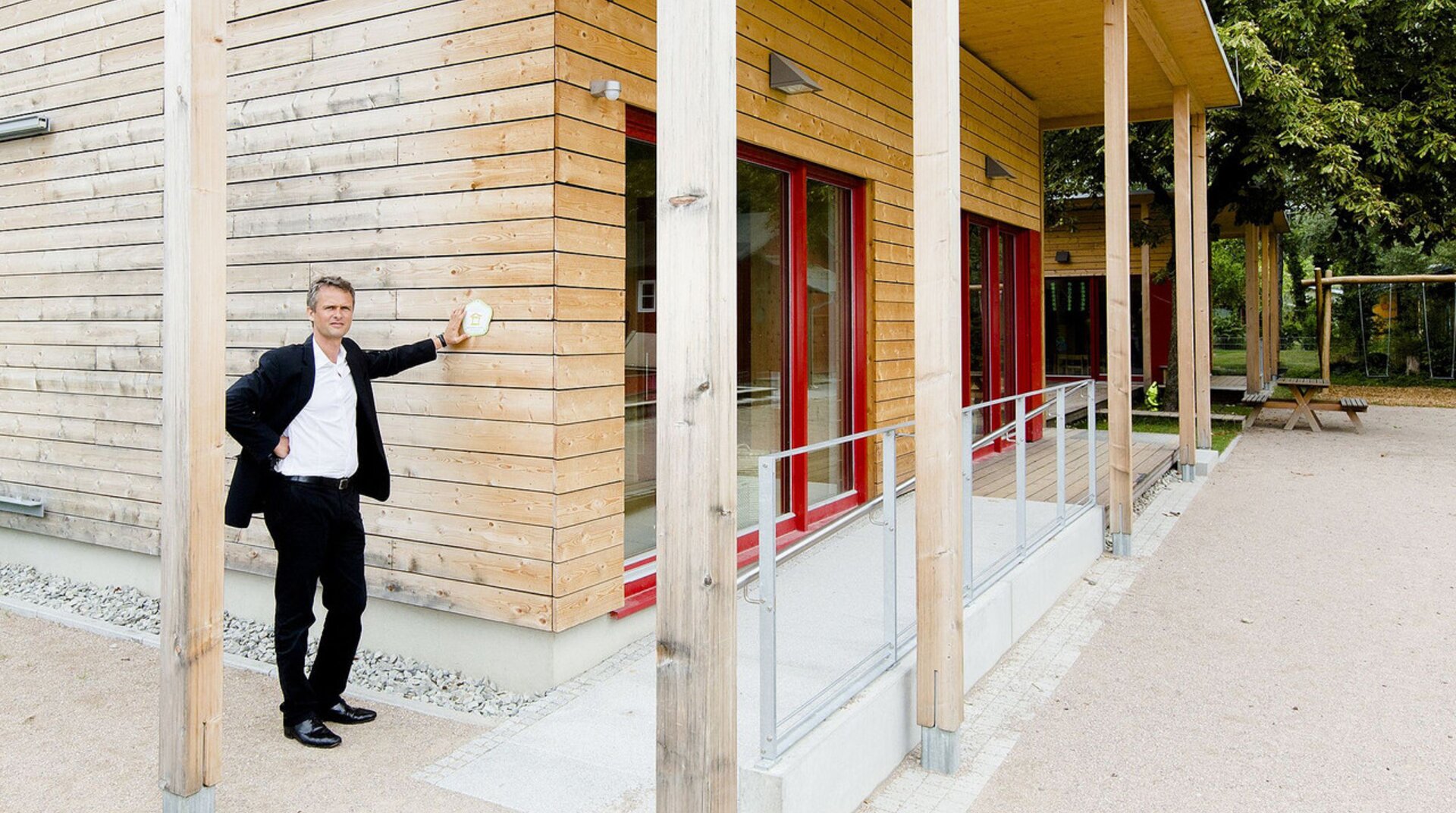 KiTa Urachstraße, Ansicht von außen auf einen Teil der Fassade, Peter Bachmann, ein Mann lehnt sich an die Fassade