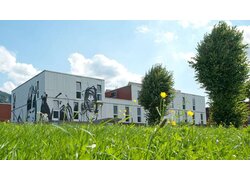 Mehrfamilienhaus , Neue Heimat Tirol, Blick auf Außenfassade, weite Distanz, Betrachtung von Wiese aus