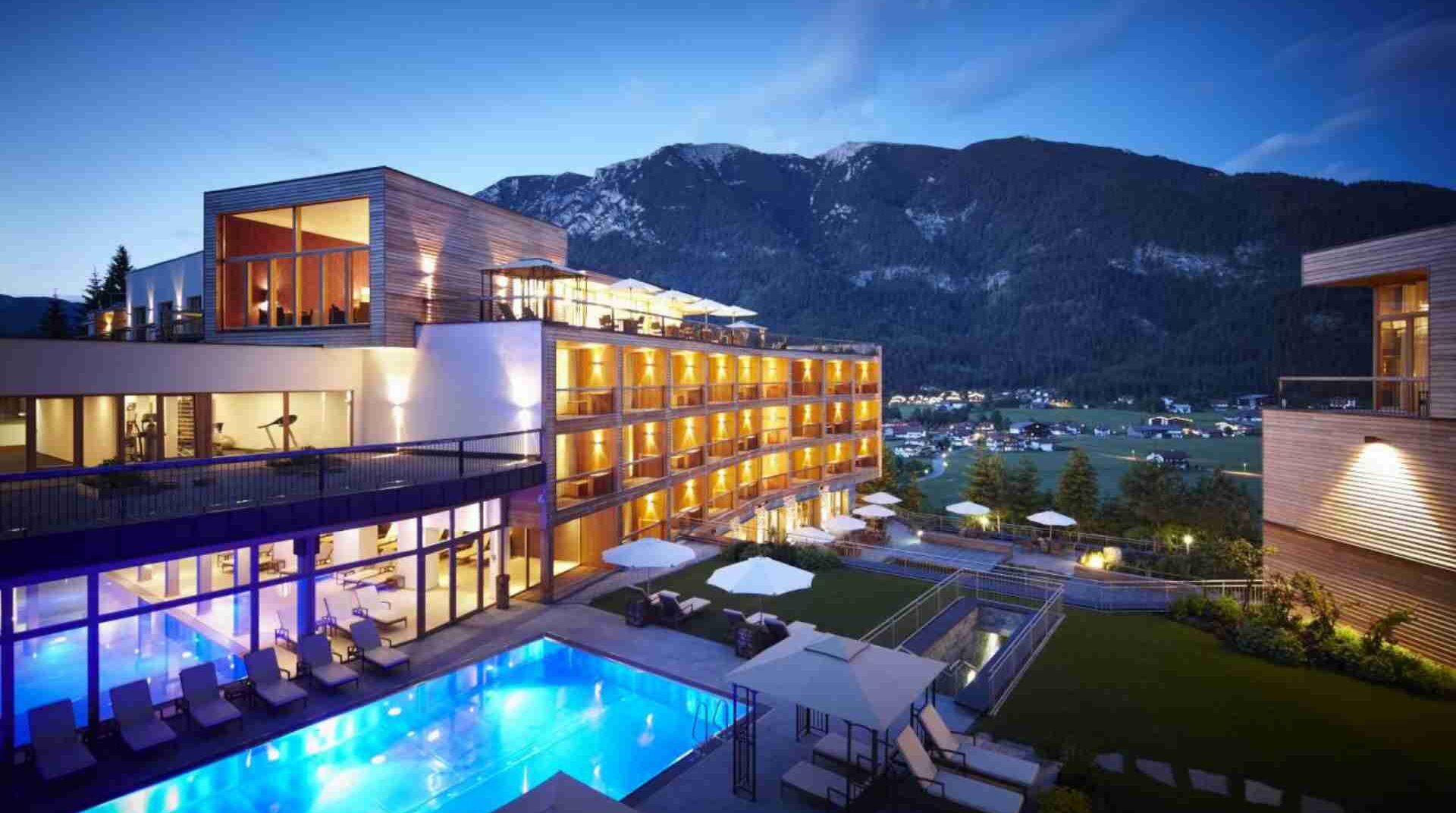 Hotel Kronthaler am Aachensee, Gebäude mit beleuchtetem Pool und Bergen im Hintergrund | © Hotel Kronthaler