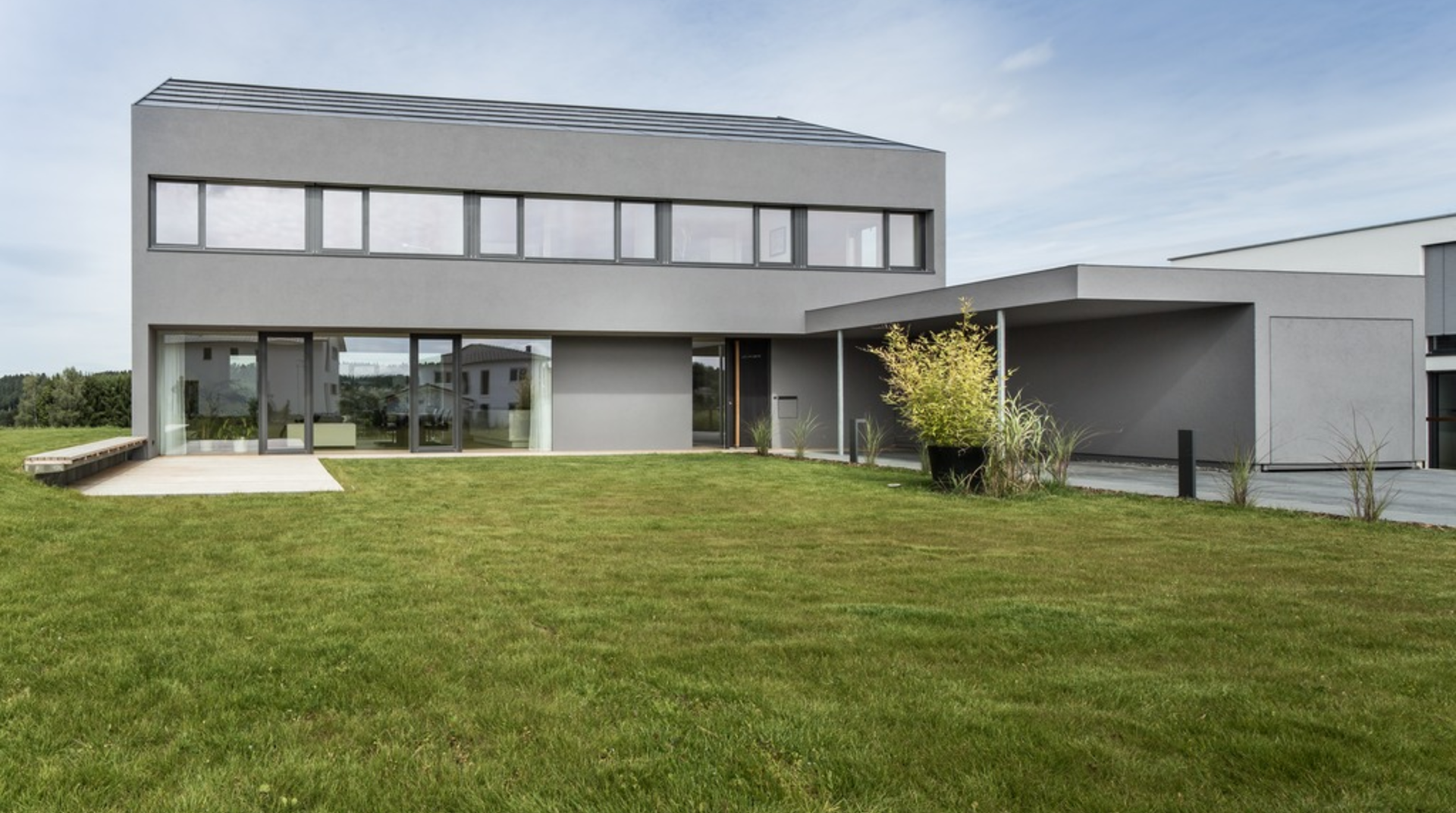 Graues Haus auf grüner Wiese mit blauem Himmel