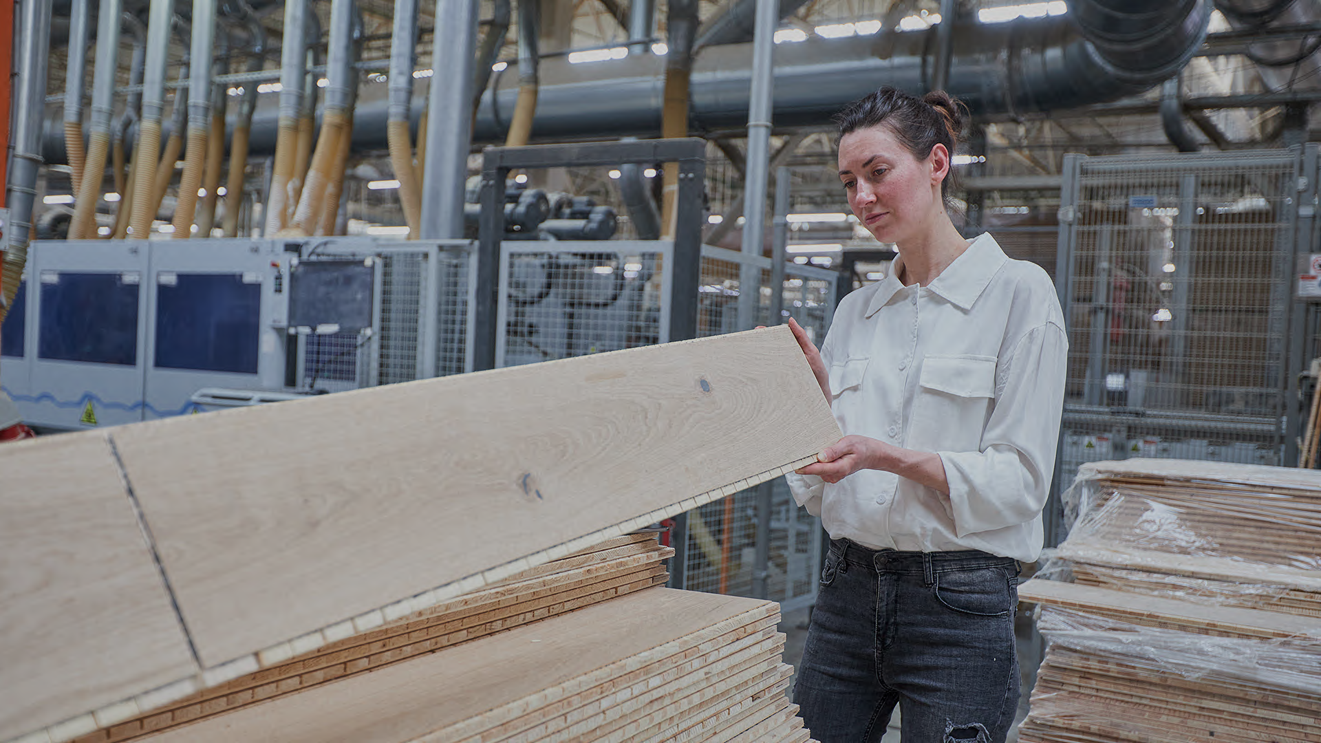 Frau inspiziert eine Holzplatte in einer Halle